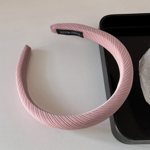Gros plan du serre-tête rembourré rose avec texture côtelée et étiquette faite main