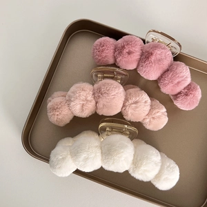 Detailed close-up of plush faux fur hair claw clips in soft pink and beige colors