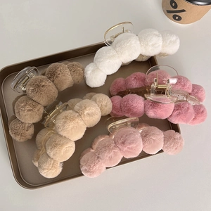 Detail of five assorted plush shark hair claws in soft winter colors on a metal tray