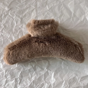 Macro view of brown plush hair claw clip showing soft velvet texture and secure grip design