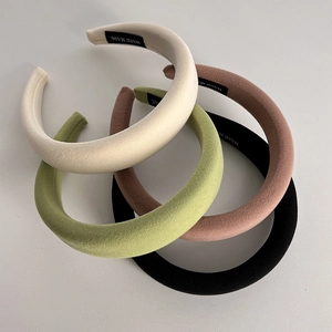 Close-up of four padded solid color sponge headbands in white green pink and black