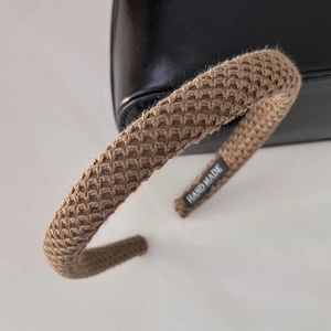 Detailed macro view of brown knitted headband with textured ribs and hand made tag