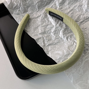 Détail d'un serre-tête en tricot vert clair avec étiquette faite main sur rembourrage
