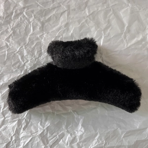Detail shot of a black plush hair claw clip with a soft faux fur texture for women