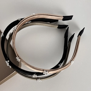 Détail de serre-têtes étroits en satin avec perles en noir, or et bronze élégant