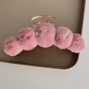 Detail of soft pink faux fur claw clip on a tray showing fluffy texture and elegant design
