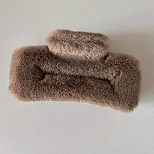 Gros plan sur la pince à cheveux en peluche marron café avec texture douce en fausse fourrure