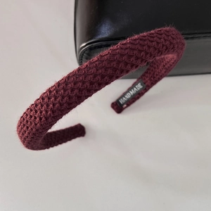 Detail shot of burgundy knitted headband featuring a handmade label and soft wool texture