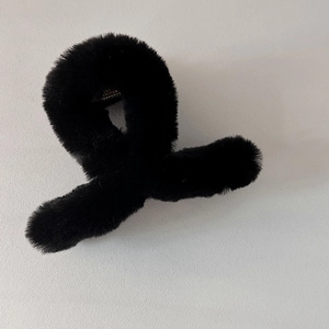 Détail d'une pince à cheveux en peluche noire avec fausse fourrure douce et attache métal
