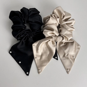 Detail of satin scrunchies in black and champagne with long ribbon and white pearls