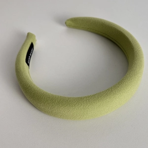 Detailed texture of grass green sponge headband with a black hand made label on inner side