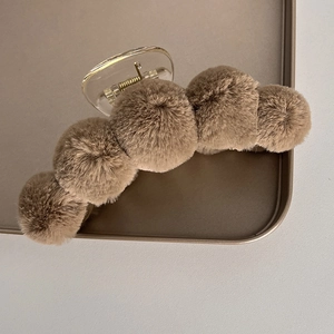 Detailed view of plush faux fur brown balls on a large hair claw clip for autumn