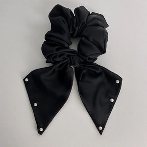 Detail of black satin scrunchie with long ribbons and elegant white pearl edges