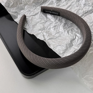 Détail du serre-tête tricoté gris montrant l'étiquette faite main et le tissu