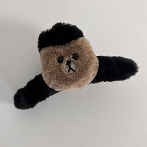 Gros plan détaillé d'une pince à cheveux ours en peluche douce, bicolore noir et marron