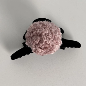 Top-down view of a plush pink curly faux fur winter hat with soft textured material