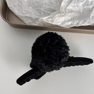 Macro detail of soft black plush faux fur ball hair claw clip for autumn and winter styles