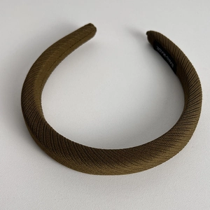 Detail shot of olive green ribbed fabric headband showing handmade label and texture
