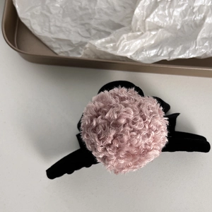 Detail of pink curly plush faux fur ball on black claw clip for autumn and winter styles