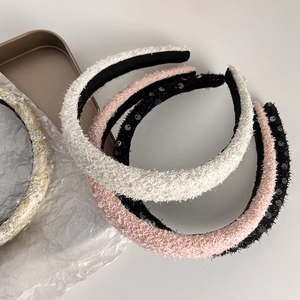 Detail of four thick tweed sponge headbands in white pink and black colors