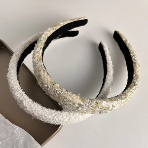 Detail of white bouclé and tweed headbands with sequins on a golden tray