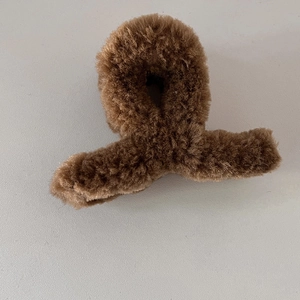 Gros plan sur la pince à cheveux en fausse fourrure marron foncé pour un style élégant