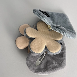 Detail of warm beige plush flower hair clip with silver metal clip and gray beret
