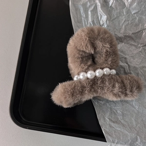 Dettaglio macro della molletta per capelli in peluche marrone con cinque perle eleganti
