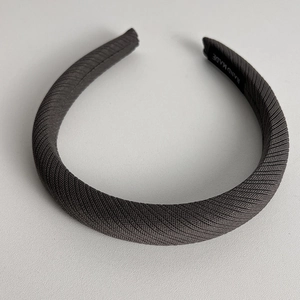 Detailed view of dark grey sponge headband with knitted texture and handmade label