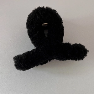 Détail de la pince à cheveux en peluche noire avec ressort métallique pour coiffures élégantes