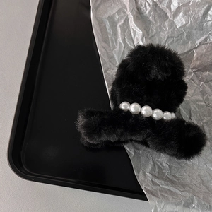 Dettaglio della pinza per capelli in peluche nera con eleganti perle per lo styling