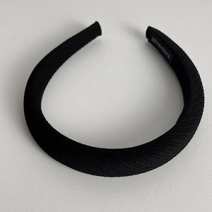 Detail of black twill fabric headband featuring a hand made woven label on the inner tip