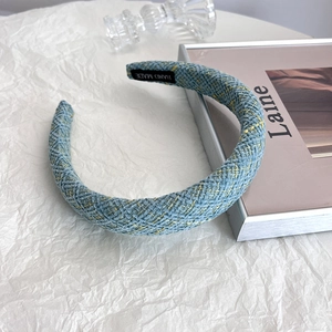 Close-up of light blue tweed headband with woven yellow lines and hand made label