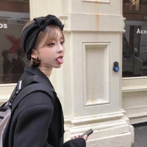 Side view of a black knitted wide headband featuring a large bow on a model