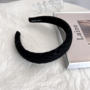 Detail of black tweed headband showing thick texture and HAND MADE inner logo