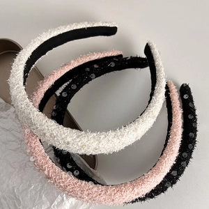 Detail of sequined padded headbands in white, pink and black with soft plush texture