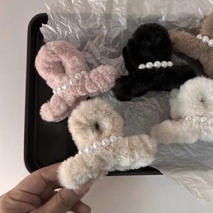 Dettaglio delle mollette per capelli in peluche con perle in rosa, nero e beige