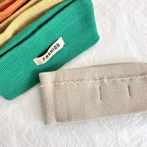Dettaglio delle fasce in maglia a coste in verde, beige e arancio con etichetta