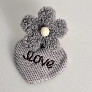Close-up of plush flower hair clip with heart-shaped base and Love embroidery detail