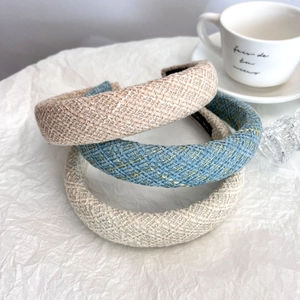 Three elegant tweed headbands in beige, blue, and cream colors on a white background