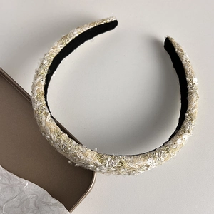 Close-up of elegant tweed headband with gold metallic threads and shimmering sequins