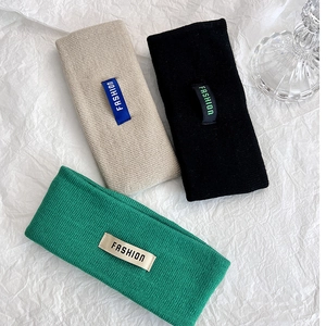 Dettaglio di fasce in maglia nei colori beige, nero e verde con etichette moda