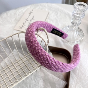 Detail of purple tweed headband with gold thread and handmade label in a luxury setting
