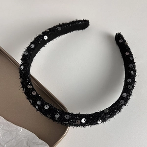 Detail of black tweed headband with silver sequins on a minimalist grey background