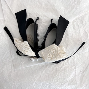 Detail of bow banana clip with black satin, white lace embroidery and pearl charms