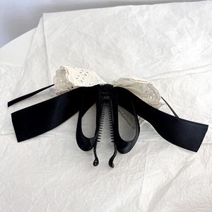 Detail of elegant black satin bow hair clip with white lace embroidery and banana clip teeth