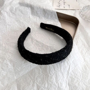 Detail view of handmade black tweed headband with sparkling texture and inner gold lettering