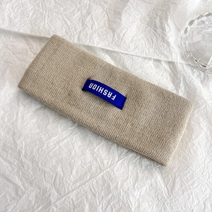 Dettaglio fascia in maglia beige con etichetta FASHION blu su morbido tessuto a maglia