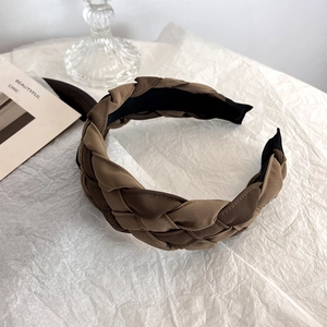 Detail of a wide brown braided headband with non-slip lining on a white background