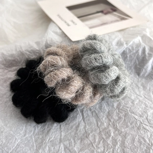 Three wool knit hair scrunchies in black, gray and coffee on a minimalist white backdrop